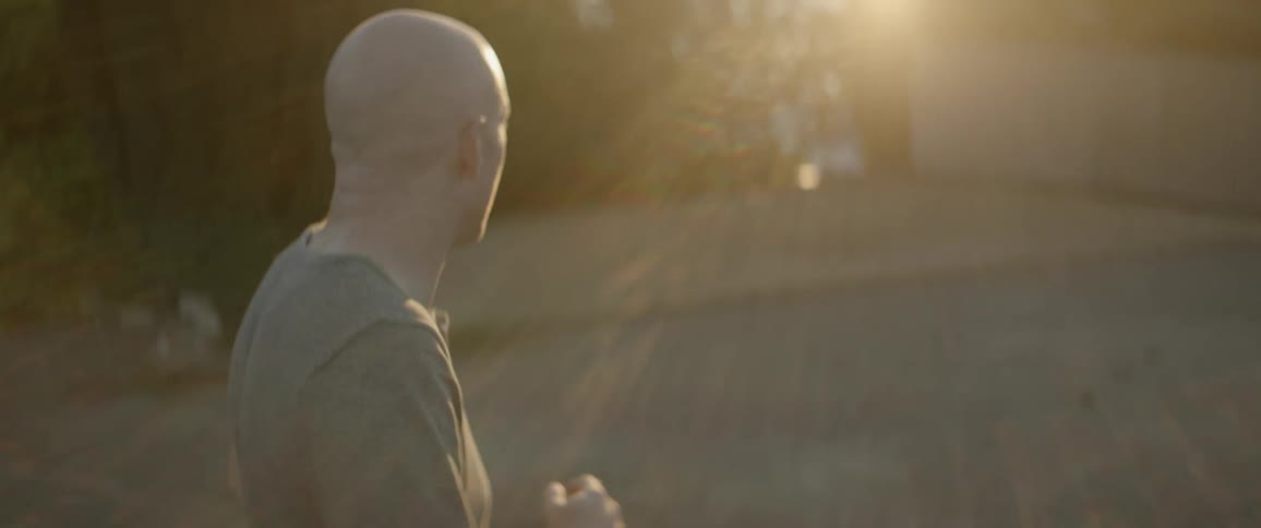 Bald man runs then turns to look towards the bright sun