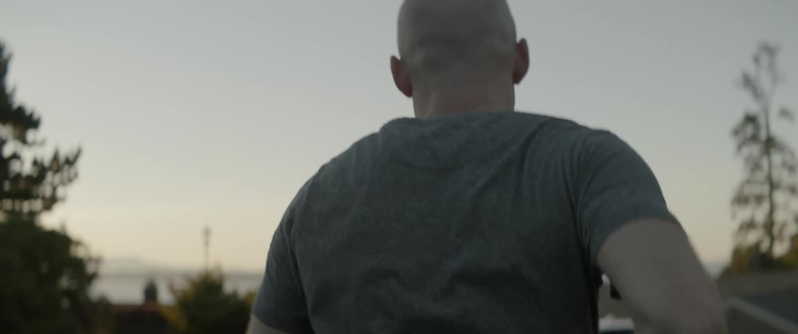 A man runs by a car and some trees at sunset