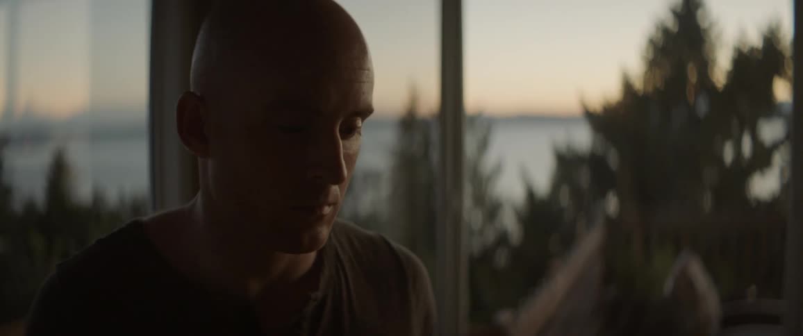 Man standing on a porch at sunset looks down