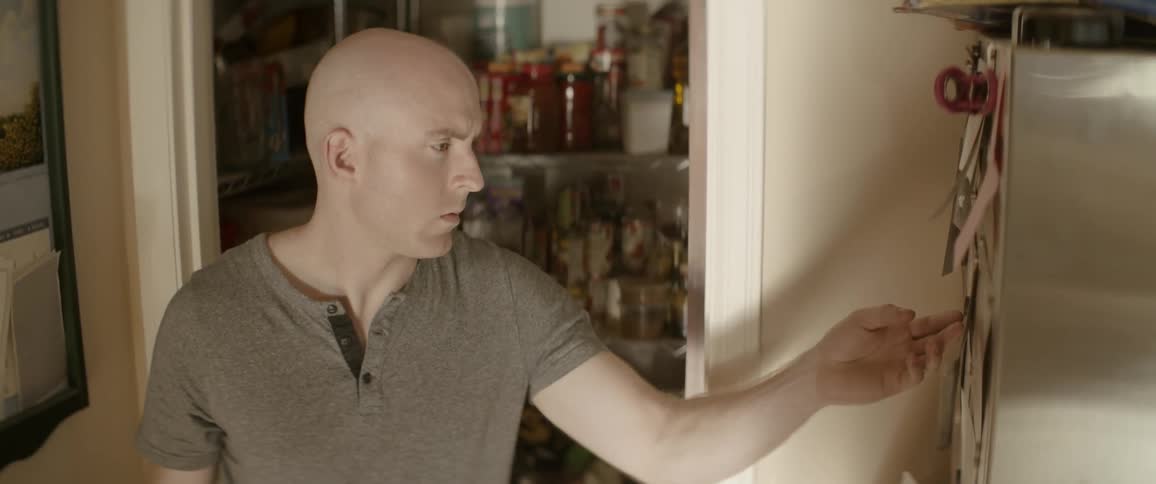 Bald man reaches for something on the wall
