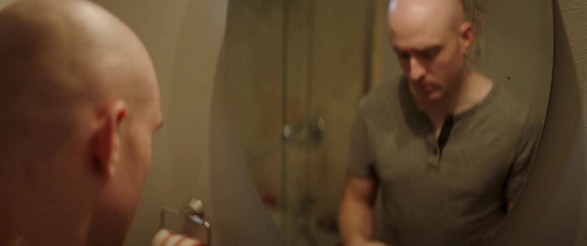 The man stands in front of a mirror before turning away