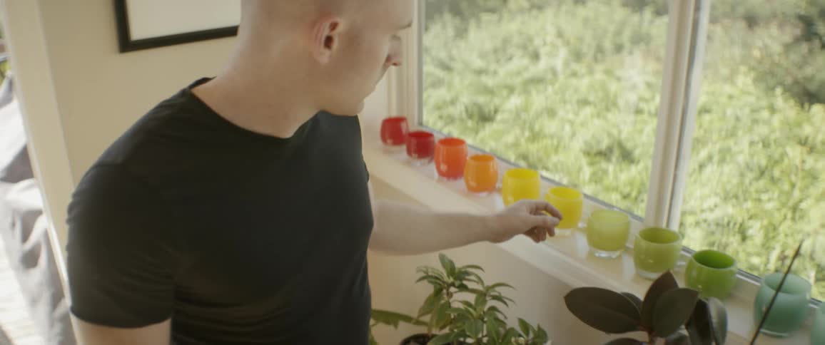 The man leans over the windowsill flicking the glasses