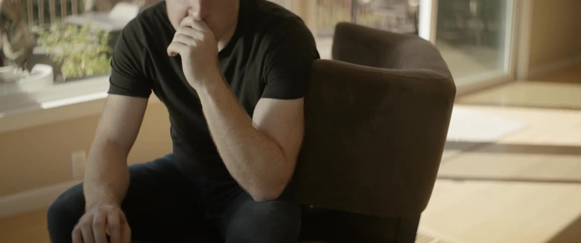 Man sits on a chair tapping his fingers on table and then walks away