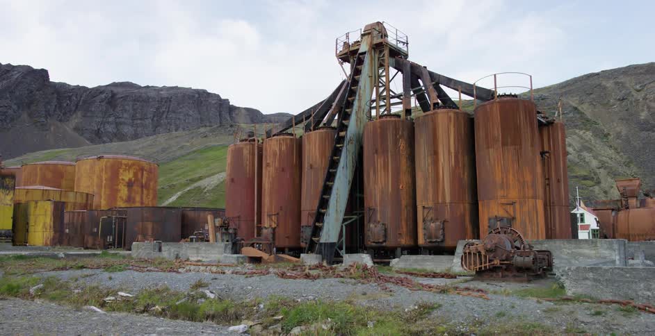 Large, rusted vats located near mountains