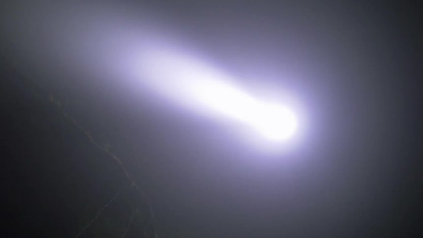 A helicopter shines a spotlight at night