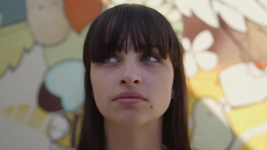 Woman with bangs stand in front of wall with graffiti