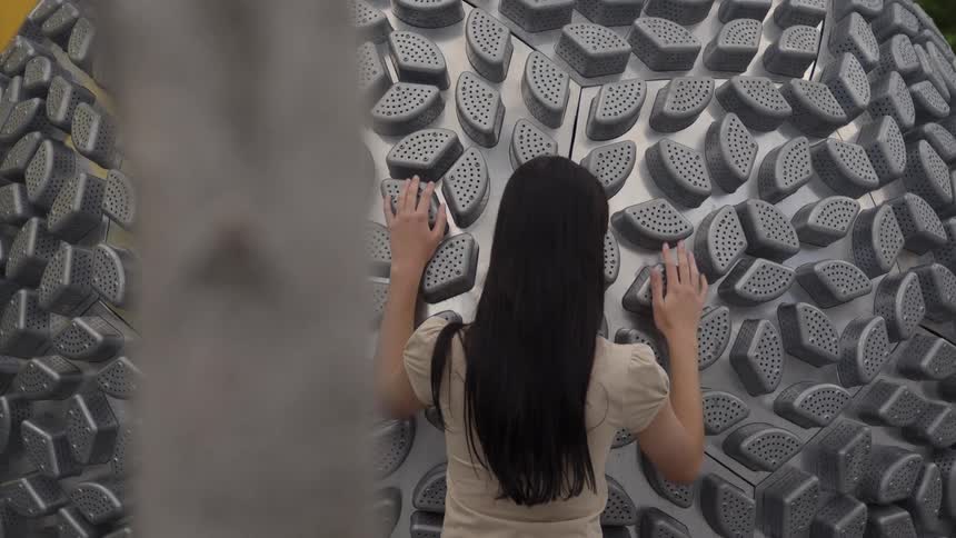 The view is of a young woman touching metal sculpture
