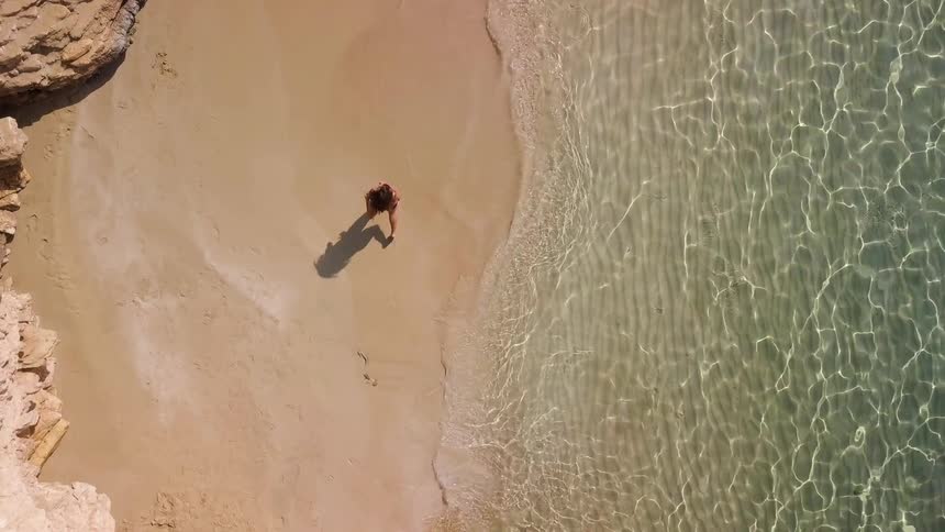 A woman running on a beach as the water crashes up onto the sand