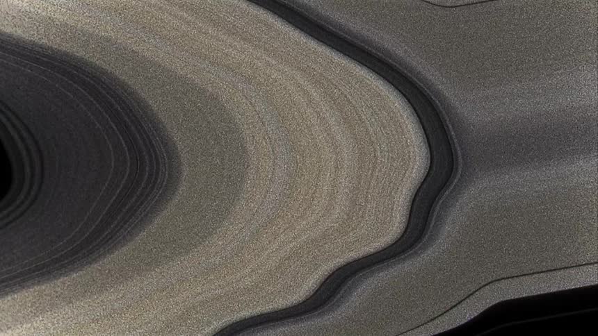Distorted grainy black and white footage of the rings on the planet saturn