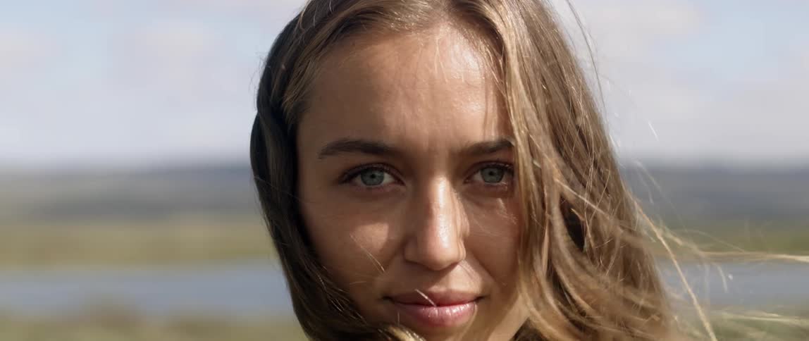 A woman stands smiling on a windy day