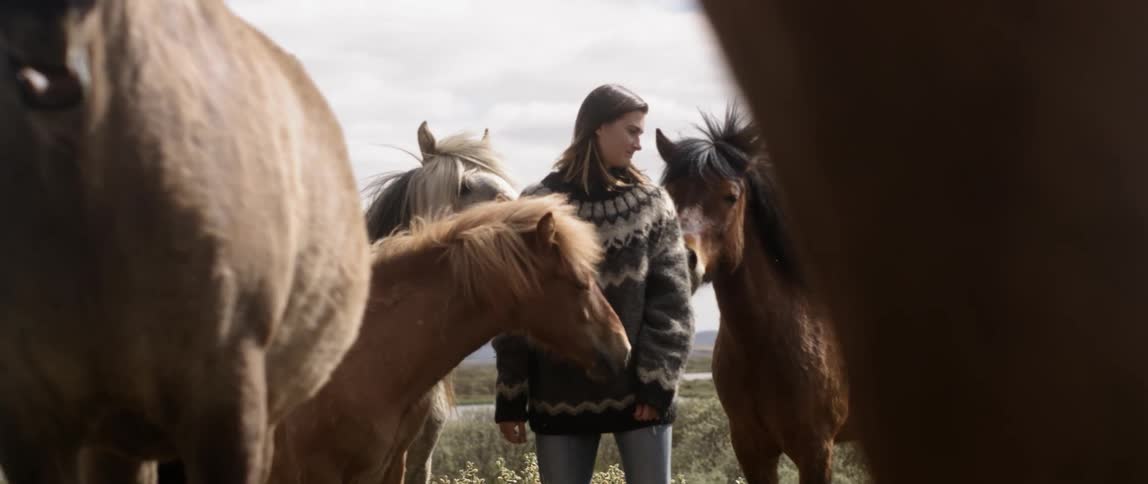 A woman stands with horses on a ranch