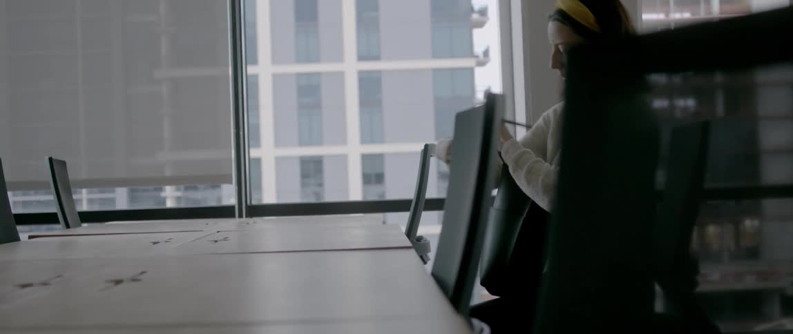 Young woman sits down in a chair at a table and opens her bag