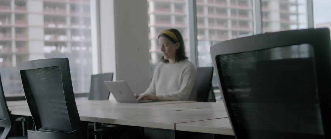 A female in an office sitting at a desk using a laptop