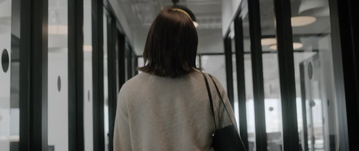A woman walks down a hallway made of windows