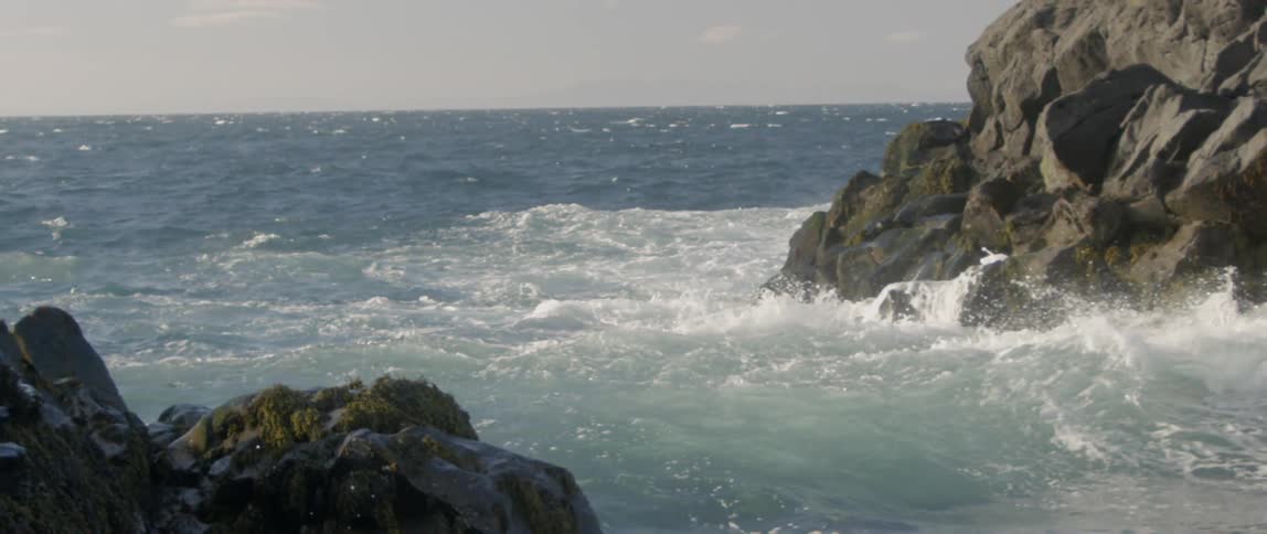 The waves crash as they reach rock formations near the shore