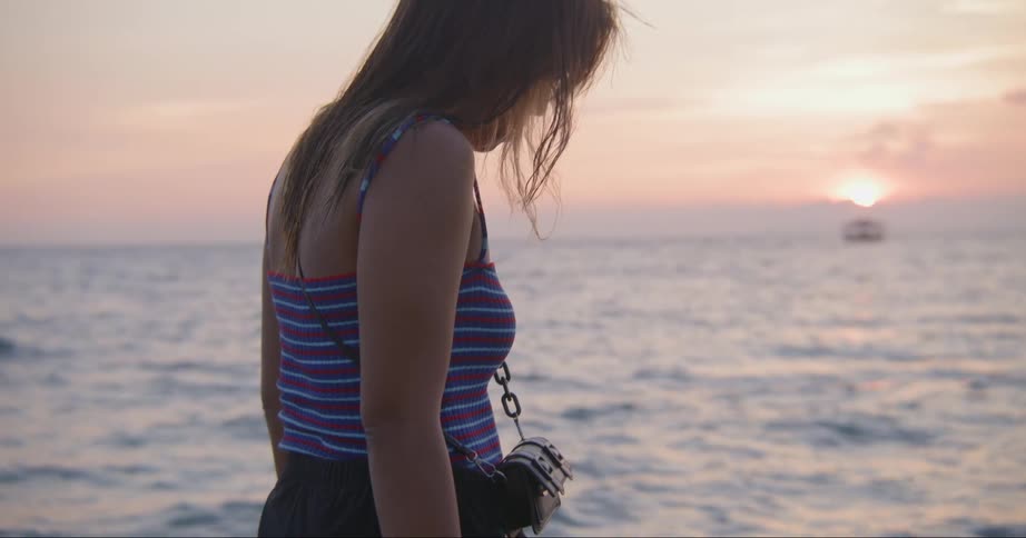 A woman walking alone on a beach at sunset