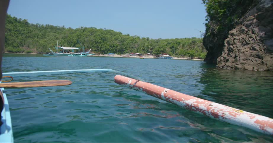 A man sits on a paddle board near a large pipe in the ocean