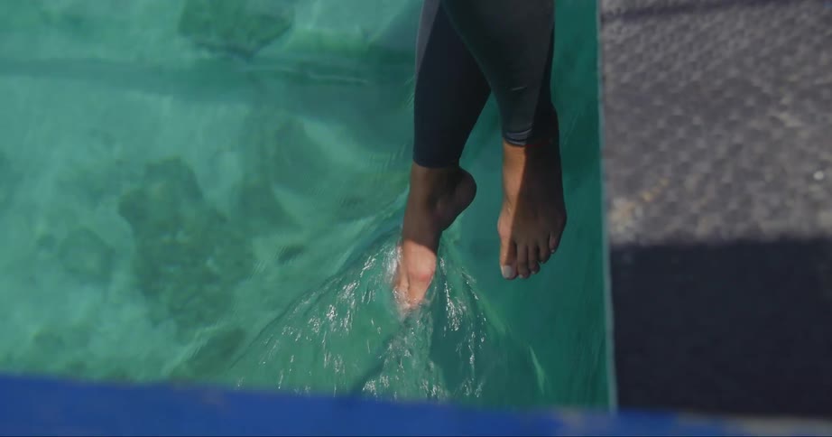 A womans foot leaves a wake as she dips it into crystal clear water