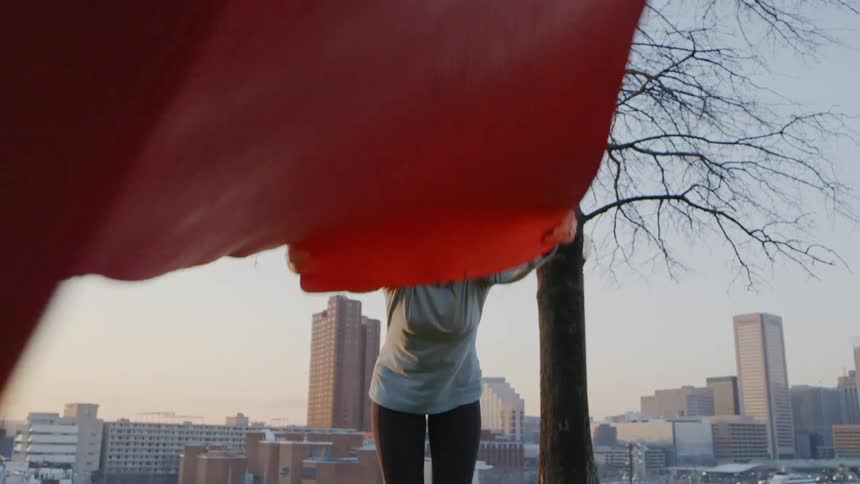 Woman unrolls a yoga mat outside in the city
