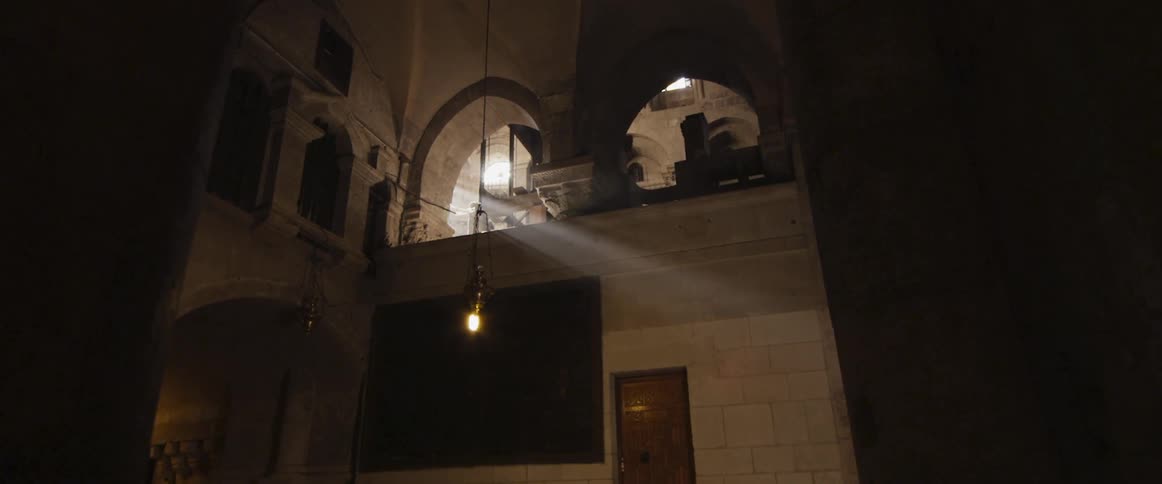 A light hangs down from the ceiling near an archway of a building
