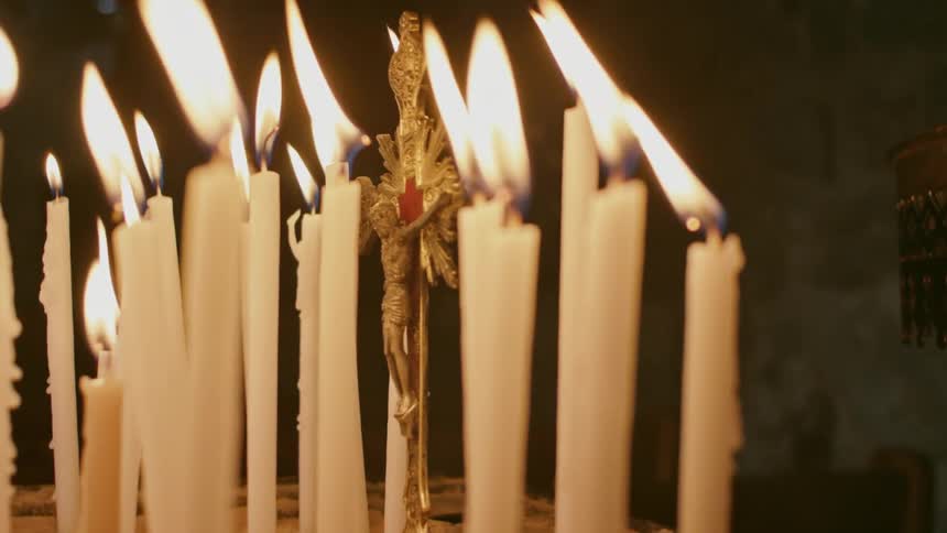 Candles burn around a crucifix