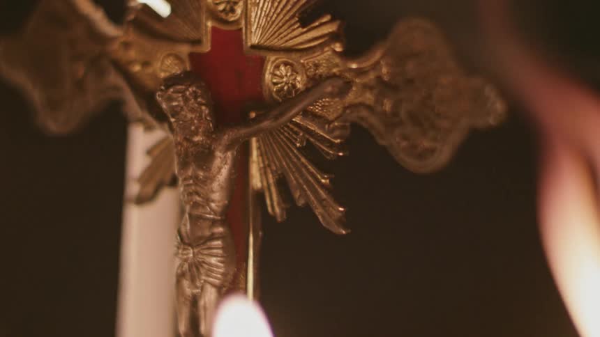 Candle flames flickering near a crucifix