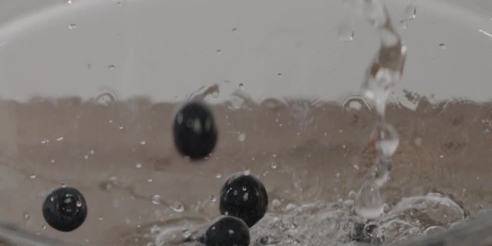 Water and berries fall into a bowl