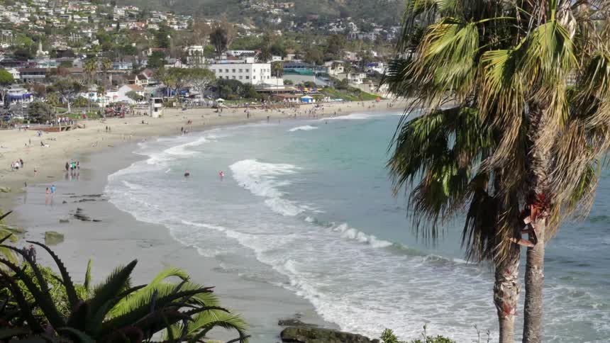 Beach-goers enjoy the sunny weather as waves crash ashore