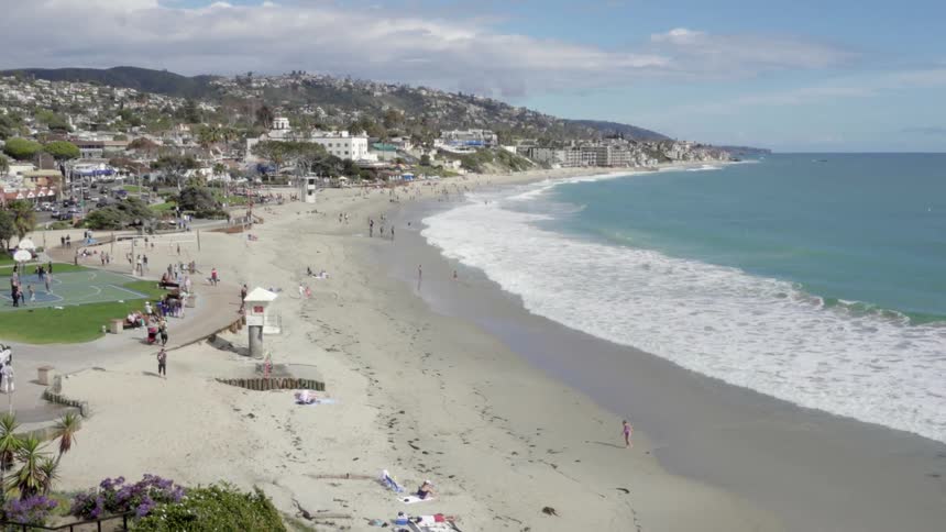 Beach-goers enjoy the sunny weather as waves crash ashore