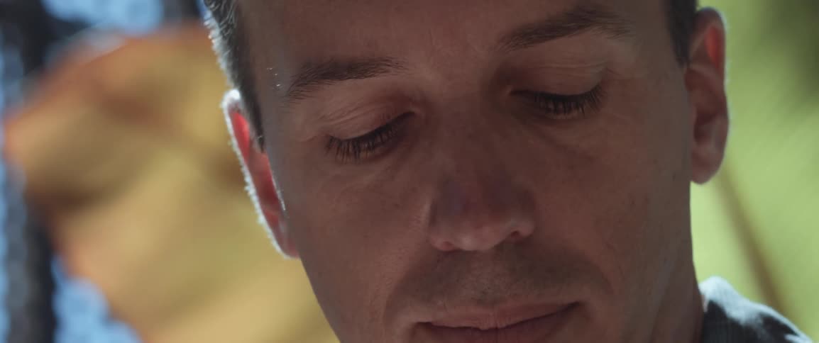 A man looks around and then down as if noting something on a paper or computer looking bored