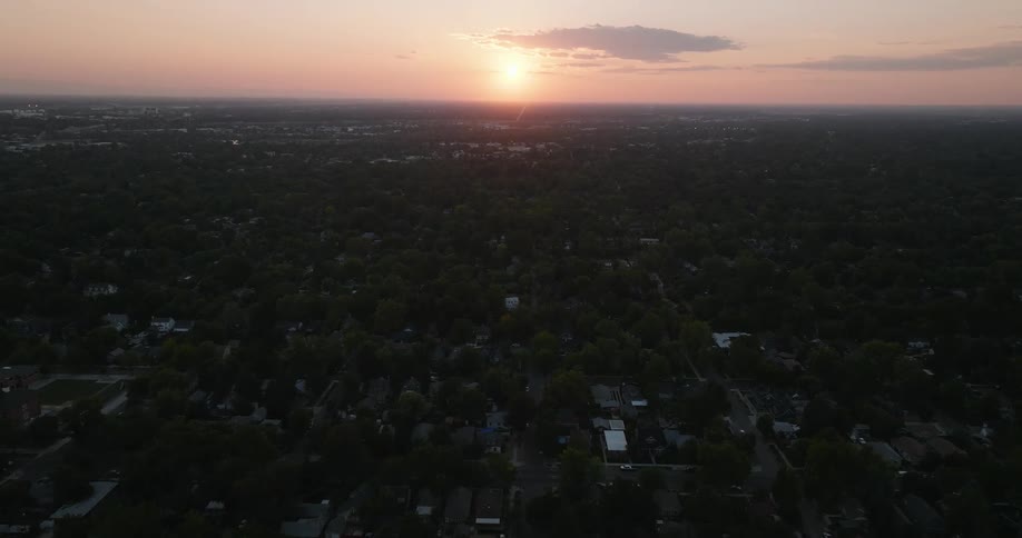 An aerial of a suburban neighborhood as the sun is setting on the horizon