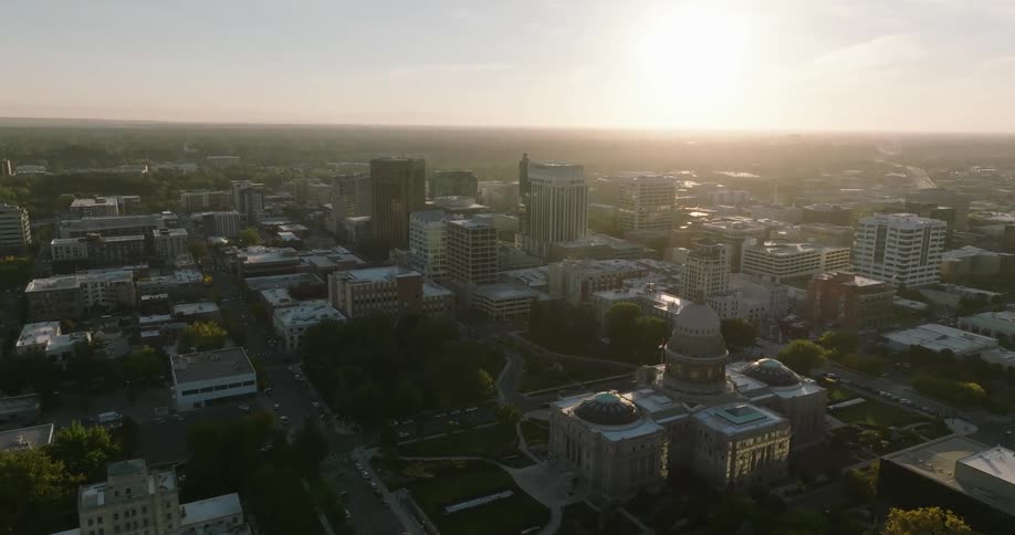 City stretches between capitol building and sun shining on red horizon