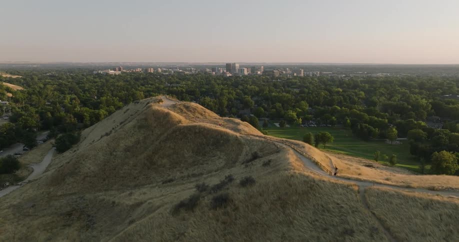 Aerial view of city skyline seen from behind a hill at sunset