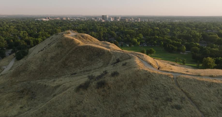People move along path topping hill a distance from skyline