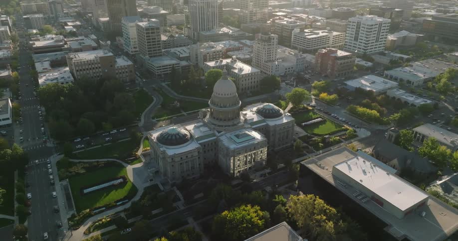 A domed building stands downtown among towers and office buildings as traffic moves on the streets and people walk on the sidewalks