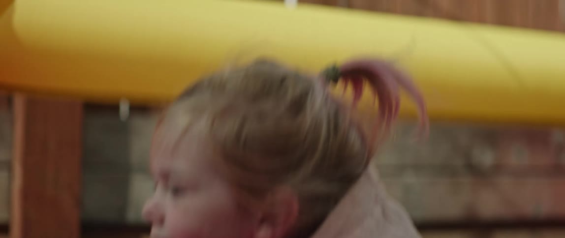 Girl laughs while catching an squat transparent inflated ball in a playground