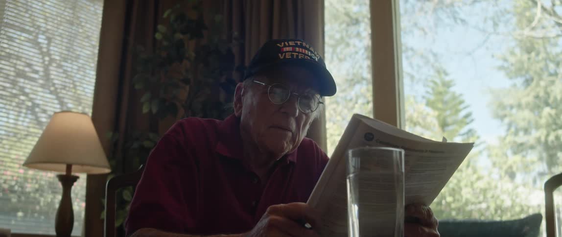 An elderly man is reading something in the day time