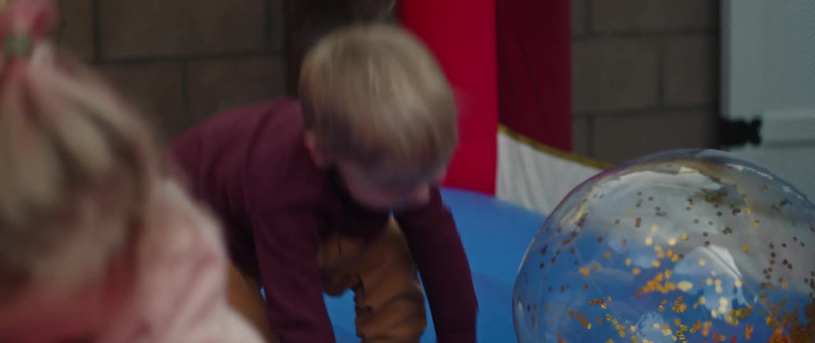 A young boy and girl play with balls on a bounce structure