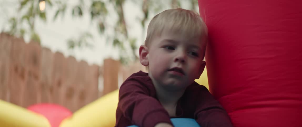 Young boy and girl play with inflated bounce house in yard