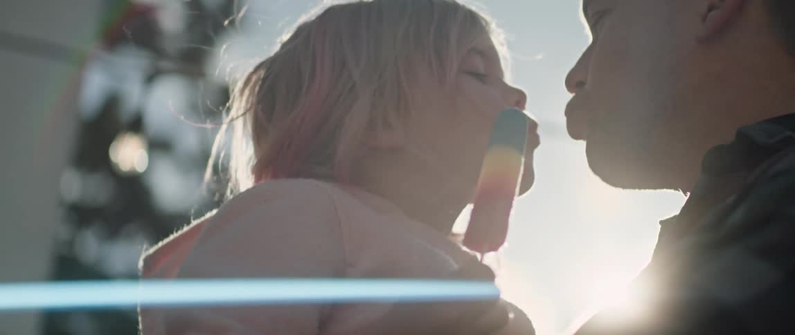 Girl eating popsicle kisses her father on a sunny day