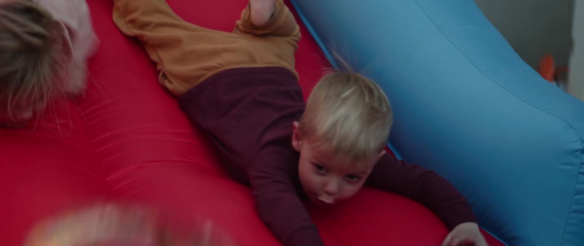 Two young kids playing in bouncy house or up slide sliding down and running around