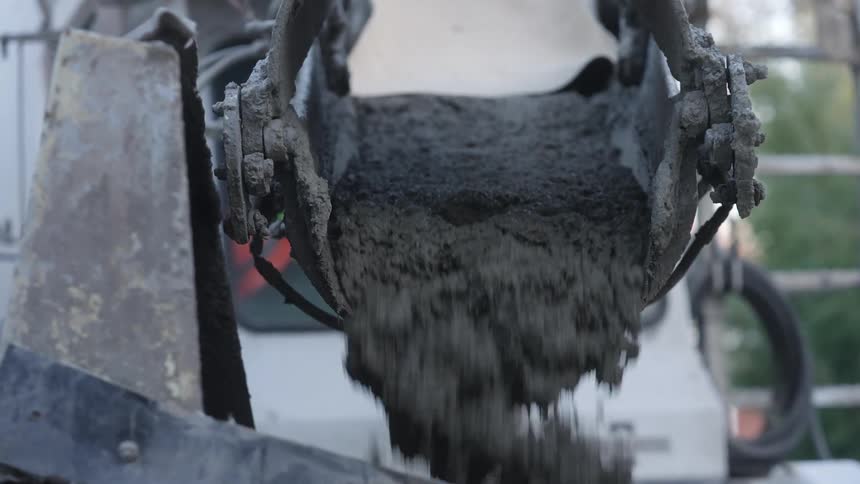 A cement truck pouring cement out of a ramp