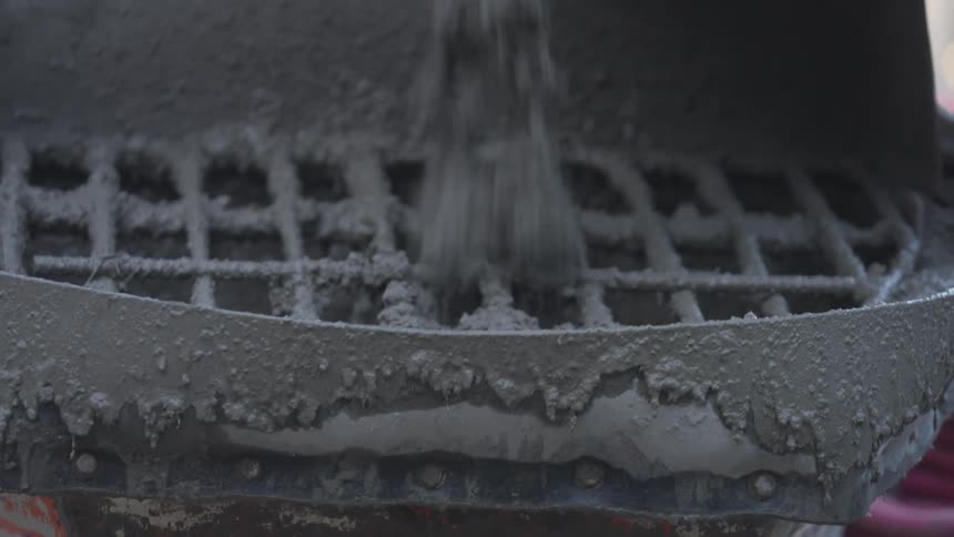 Concrete falls from spout onto grill topped container