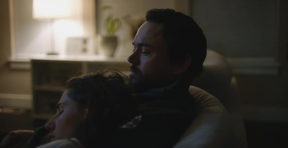 A young couple is sitting on the couch and watching television