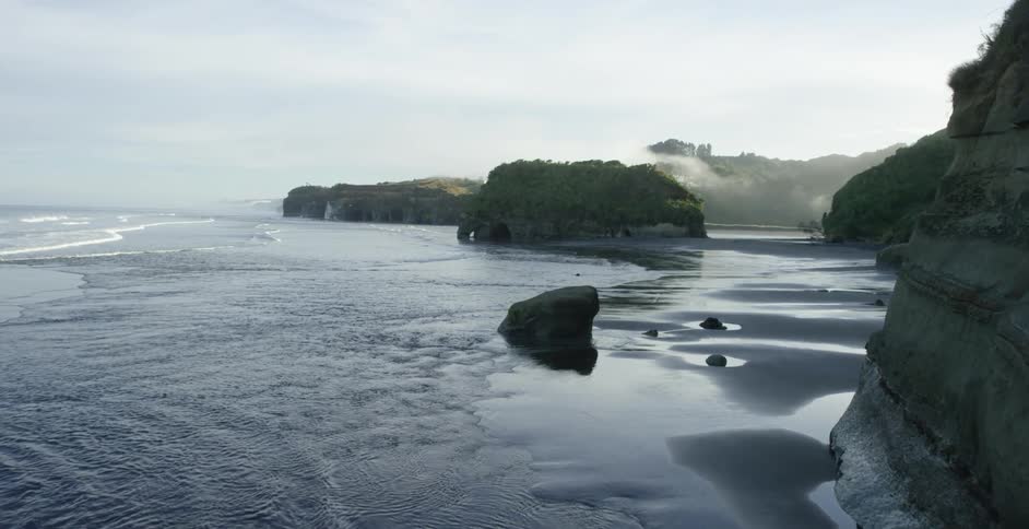 Aerial view of ocean and wet sand beach at sunset