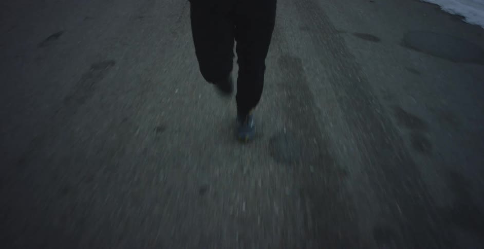 A persons legs as they run on pavement near snow