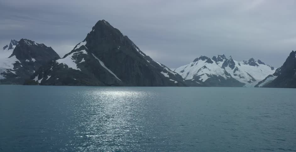 A mountain near a body of water on a cloudy day