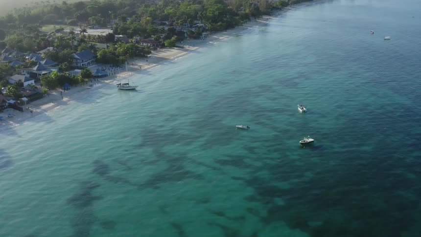 High above the ocean and coastline with boats scattered in the bay