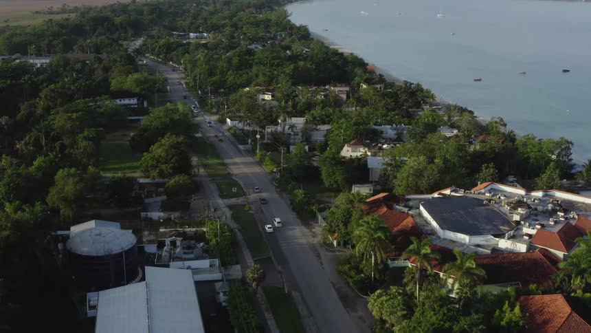 Aerial view of suburban area near coast lake or ocean with highway and lots trees and small boats