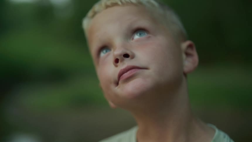 A young boy looks upwards with a pleasant expression on his face